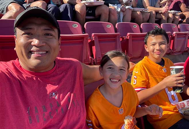 Christian with his children in the bleachers at a sporting event