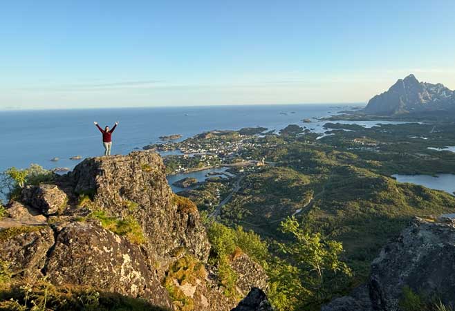 Zoomed out view of Katie posing on top of a mountain
