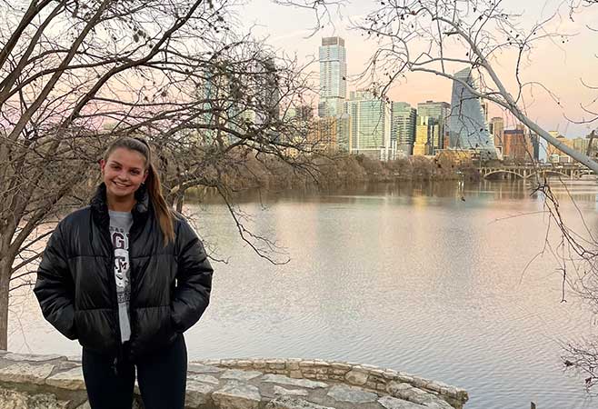 Taylor posing in front of a river and city skyline