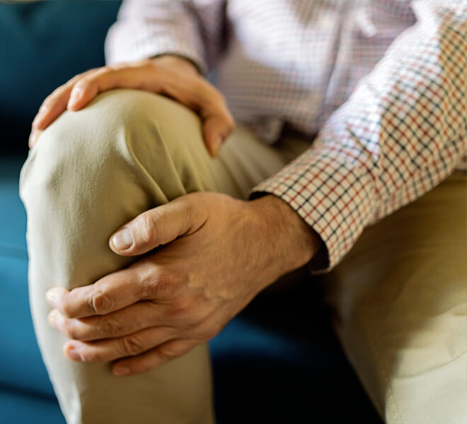 Man recovering from arthritis surgery holds sore knee