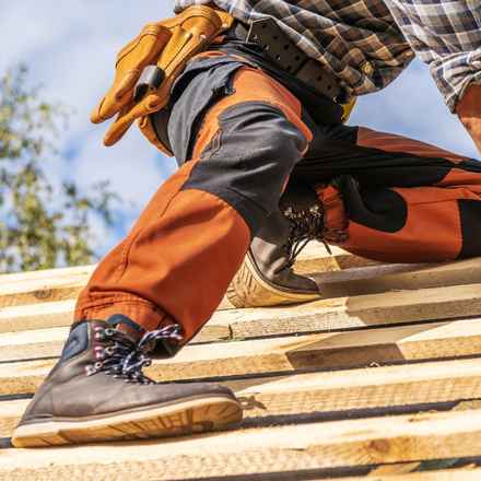 man kneeling while working on a roof