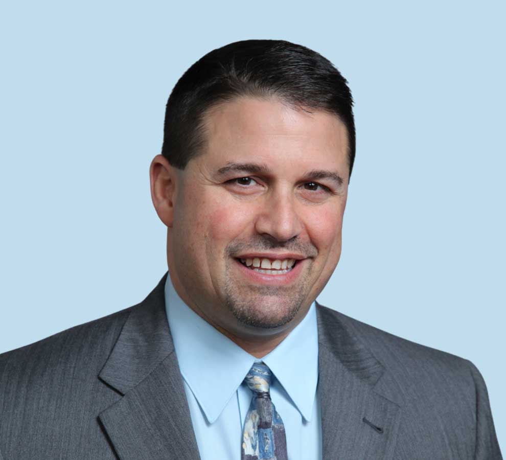 Anthony F. Infante, DO professional headshot wearing gray suit with painterly tie