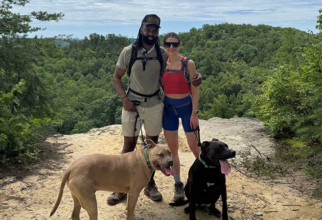 Dr. Likine and partner hiking with two dogs.