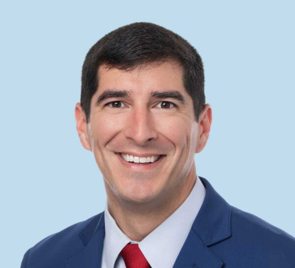 Dr. Eric Villarreal headshot wearing professional jacket with red tie