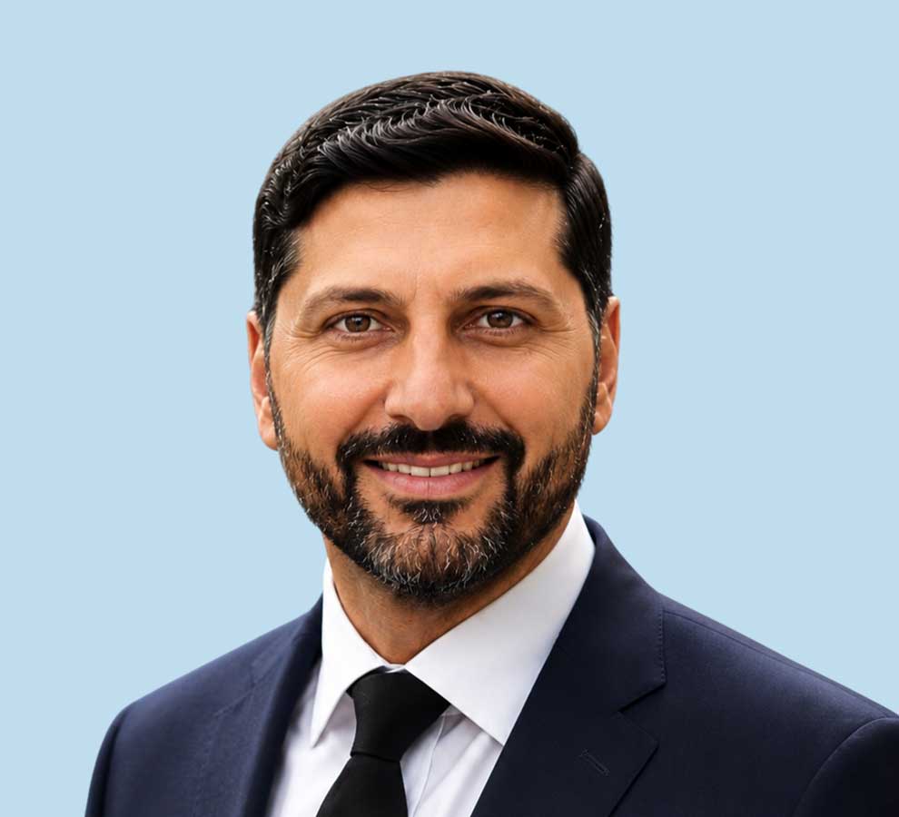 Dr. Hassan Mir professional headshot wearing dark suit and tie