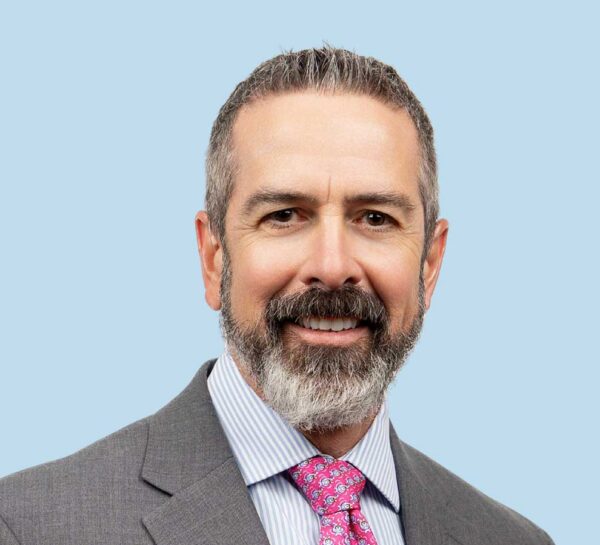 Dr. Peter Lopez professional headshot wearing a grey suit and pink tie.