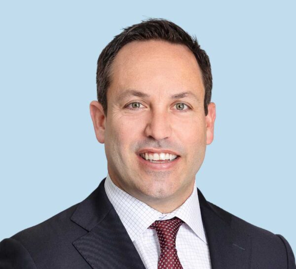 Dr. Samuel Swiggett professional headshot wearing black suit and red tie